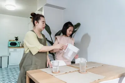 Family pouring water from a filter jug at a kitchen table in a rental apartment, one of the best water filter options for renters in Australia