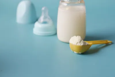 Infant formula powder scoop beside a baby bottle, made up with tap water as most Australian babies drink tap water