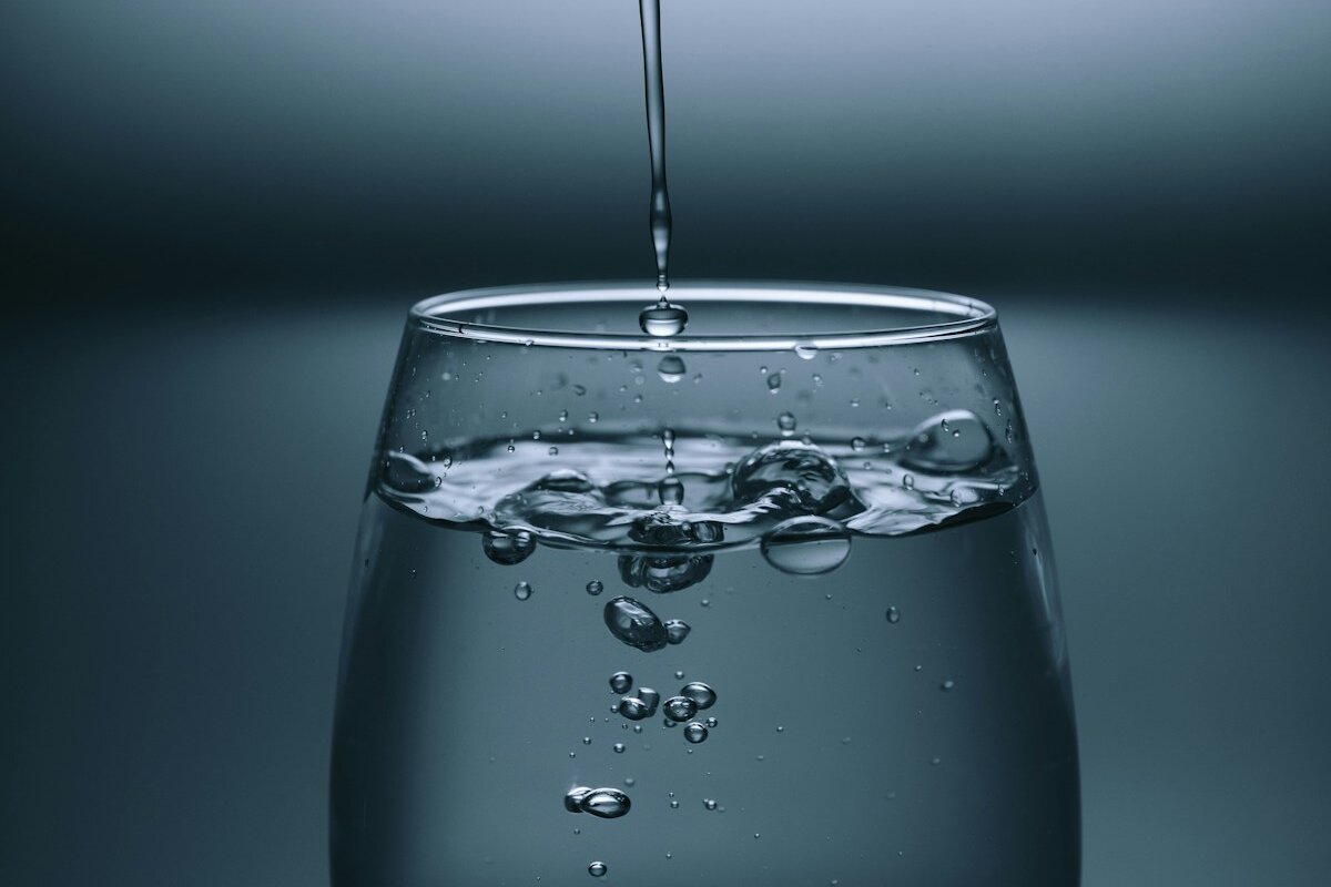 Glass of clear water being filled from a kitchen tap, representing chlorine in Australian tap water