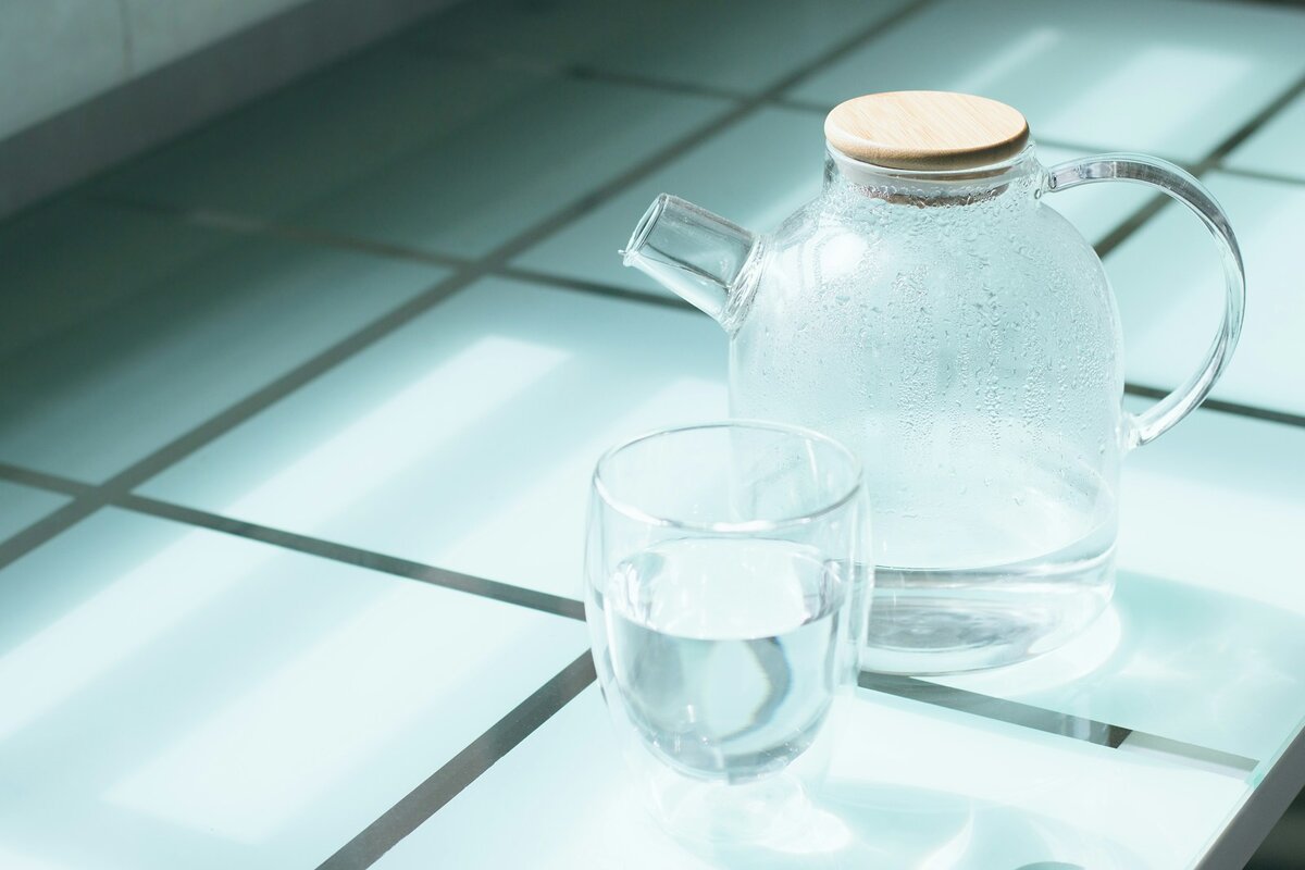 Glass jug of filtered water and a full glass on a kitchen bench, the everyday setup a Coles water filter jug is bought for