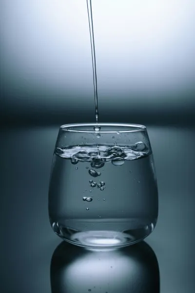 Glass of clear Australian tap water being filled from a kitchen tap, representing fluoridated drinking water