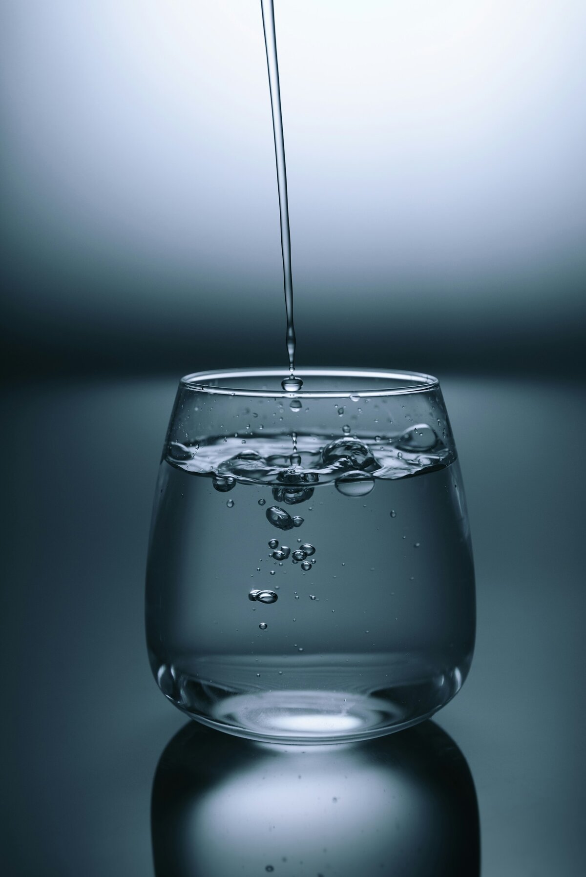 Glass of clear Australian tap water being filled from a kitchen tap, representing fluoridated drinking water