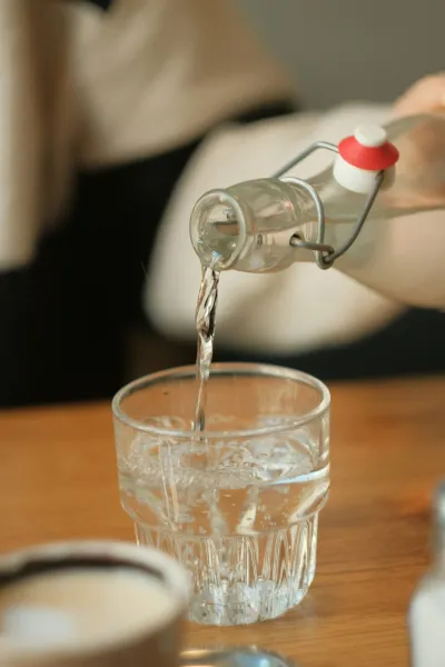 Person pouring a glass of drinking water in Adelaide, where tap water is safe but noticeably hard