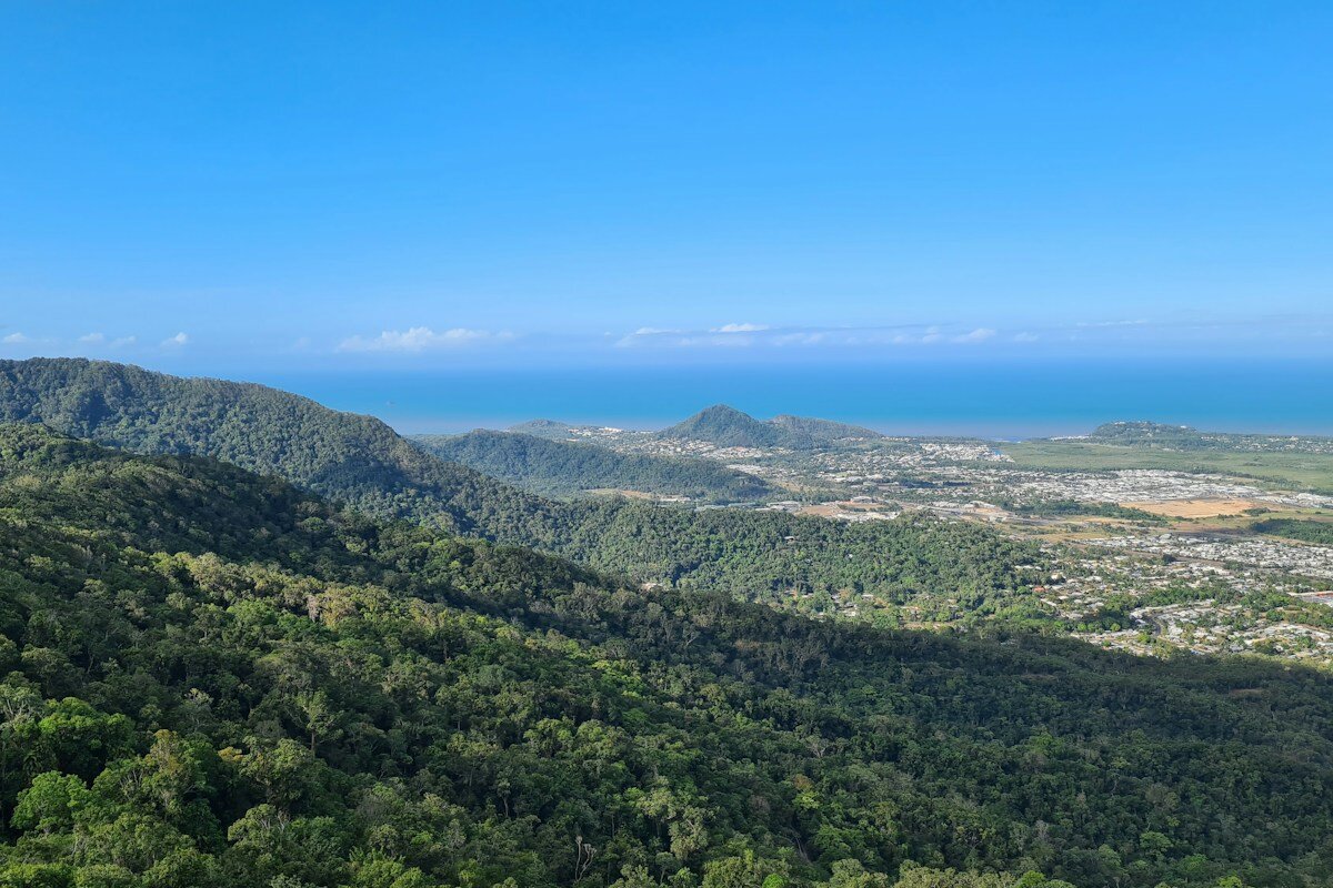 View over rainforest-covered ranges to Cairns' northern suburbs and the Coral Sea, the kind of protected catchment that supplies Cairns tap water