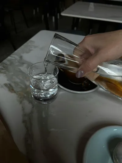 Person holding a glass of clear drinking water in a kitchen, reflecting Darwin's safe tap water supply