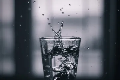 Glass of clear Hobart tap water on a kitchen bench with kunanyi / Mount Wellington in the background